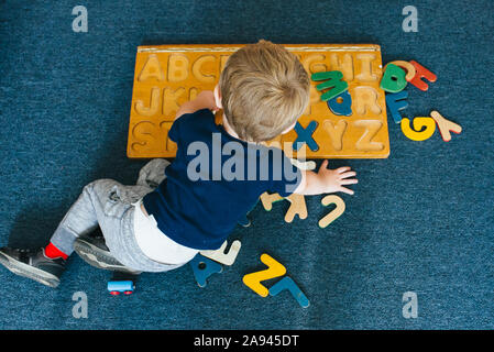 Un bambino gioca con un alfabeto puzzle. Foto Stock