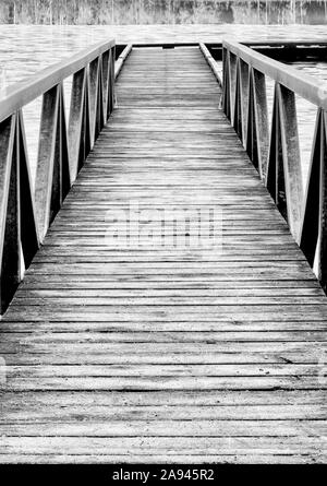 Bianco e nero di una banchina di legno che conduce ad un lago congelato; British Columbia, Canada Foto Stock