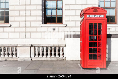 Londra casella Telefono. Tradizionale in stile antico Regno Unito telefono rosso box set contro un governo beige edificio nel centro di Londra. Foto Stock