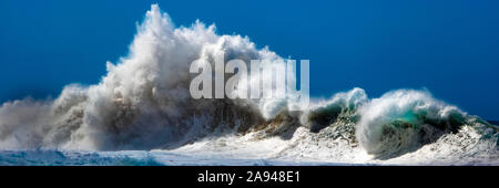 Grande onda che si infrangono dalla costa di Na Pali contro un cielo blu e luminoso; Kauai, Hawaii, Stati Uniti d'America Foto Stock