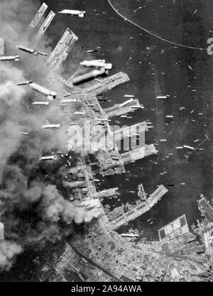 Bombe incendiarie vengono fatti cadere sopra la città di Kobe, Giappone da American B-29 Superfortresses, come pontili di sbarco e gli edifici della città stanno bruciando sotto, 4 Giu 1945 Foto Stock