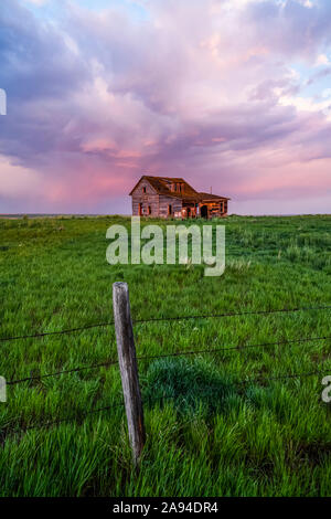 Fienile abbandonato su terreni agricoli con nubi tempeste che illuminano rosa; Val Marie, Saskatchewan, Canada Foto Stock