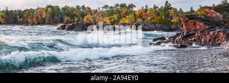 Lago Superior con una foresta in colori autunnali e le onde che si lavano sulla spiaggia; Ontario, Canada Foto Stock