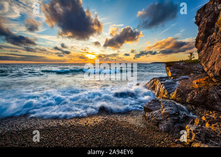 Il surf si lava a riva mentre il sole tramonta sul lago Superior; Ontario, Canada Foto Stock