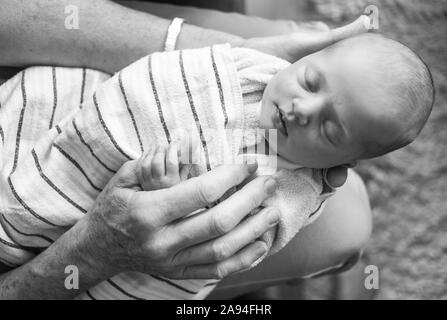 Bambina appena nata avvolta in una coperta e dormendo in grembo al padre; Vancouver, British Columbia, Canada Foto Stock