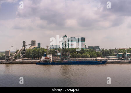 Lungo il fiume Tau, Vietnam - Marzo 12, 2019: Nhon Trach area. Sguardo diretto allo scarico barca a INSEE stazione di cemento con silos, nastro trasportatore e la sua qu Foto Stock