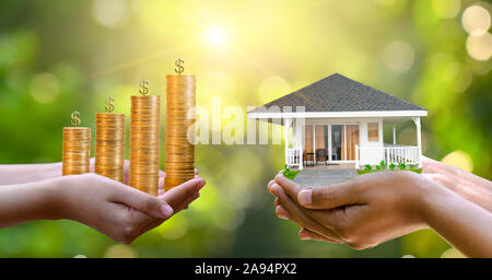 Le mani di un imprenditore tenere il denaro e l'altra mano impugna una casa. L'idea di risparmiare denaro per acquistare una casa Foto Stock