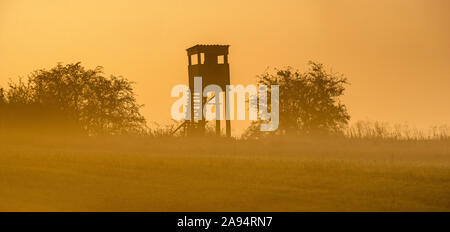 La torre della caccia durante il tramonto su una bella mattinata nebbiosa. Foto Stock