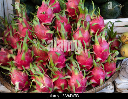 Close up dragon frutta impilate su di un piatto di bambù in un mercato all'aperto in Hoi An Vietnam. Foto Stock