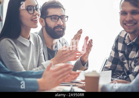 Startupers lavorando insieme in ufficio di affari che applaudono soddisfatti close-up Foto Stock