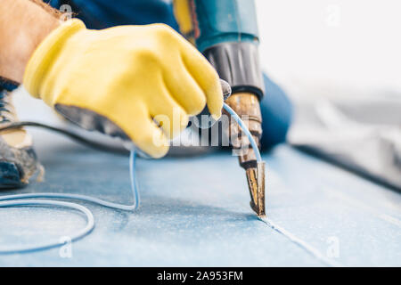 Master di saldatura del tipo macchina asciugatrice di costruzione si salda con due pezzi di linoleum mediante un cordone di saldatura Foto Stock