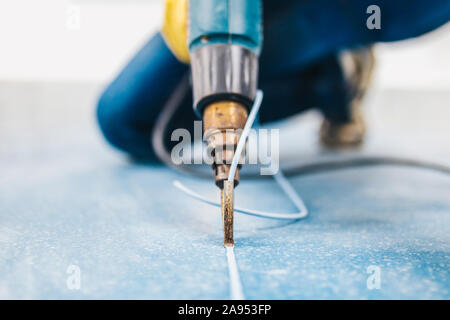 Il Linoleum spike tecnologia - macchina di saldatura con l'ausilio di aria calda nelle mani di uno specialista Foto Stock