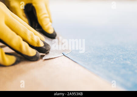 Close-up di un maestro professionalmente e professionalmente esegue il taglio del cavo in PVC dopo la saldatura a caldo omogeneo linoleum commerciale Foto Stock