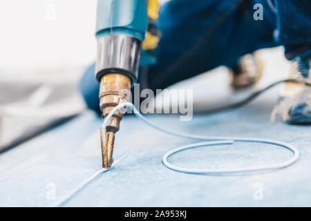 Master di saldatura del tipo macchina asciugatrice di costruzione si salda con due pezzi di linoleum mediante un cordone di saldatura Foto Stock