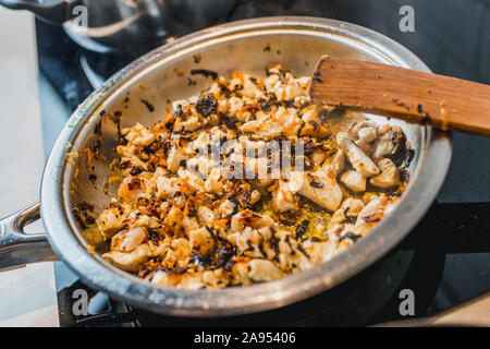 Filetto di pollo a fette, cipolle fritte e carote in una salsa alla panna in una padella - close-up - cucina casalinga Foto Stock