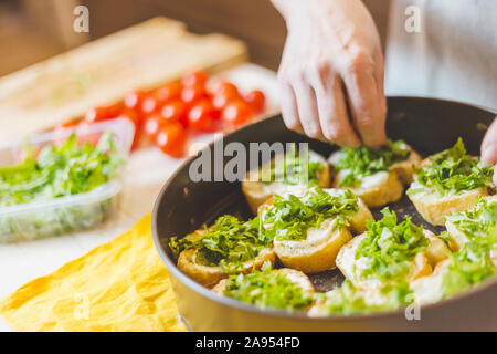Close up di senior donna mani il taglio baguette - rendendo bruschetta sandwich - cucina casalinga Foto Stock