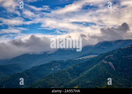 Bellezza del paesaggio di nebbia e nuvole rolling oltre la montagna boscosa. Foto Stock