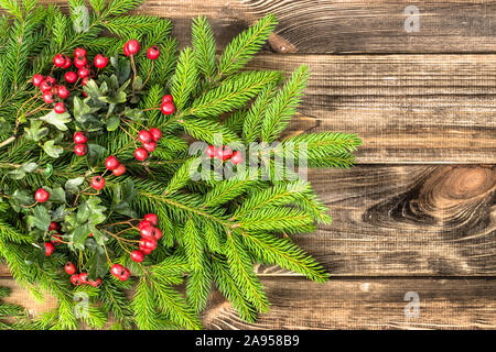 Natale abete con bacche rosse sul rustico sfondo di legno Foto Stock