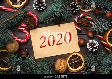 Telaio dell albero di Natale coni arance caramello dadi di canna sul legno scuro dello sfondo. Iscrizione 2020 Foto Stock