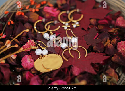 orecchini in oro con perle su foglie rosse d'autunno Foto Stock