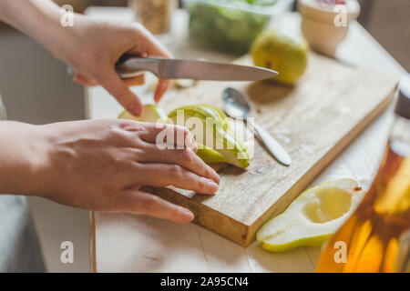 Affettare le pere in una insalata su una tavola di legno - ricetta casalinga - la casalinga con le mani in mano - rurali Foto Stock