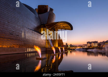 Fontana di fuoco fiamme da Yves Klein al di fuori degli illuminati Museo Guggenheim appena dopo il tramonto, Nervión River, Bilbao, Paesi Baschi Foto Stock