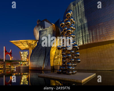 La scultura 80 sfere di acciaio inossidabile da Anish Kapoor al di fuori degli illuminati Museo Guggenheim a sera, Nervión River, Bilbao, Paesi Baschi Foto Stock