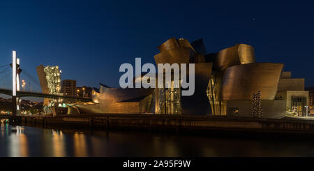 Bilbao cityscape, vista di notte attraverso il fiume Nervion verso l'illuminato il Museo Guggenheim e il Puente de la Salve, Bilbao, Spagna Foto Stock