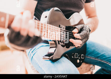 Bilanciere in black T-shirt e jeans giocando hard rock su un mancino nero chitarra elettrica Foto Stock