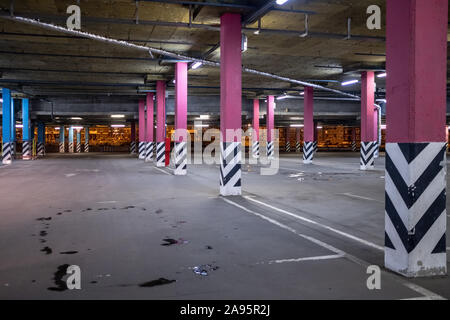 Le colonne in un vuoto di parcheggio sotterraneo di notte alla luce di illuminazione artificiale. Infrastruttura della città Foto Stock