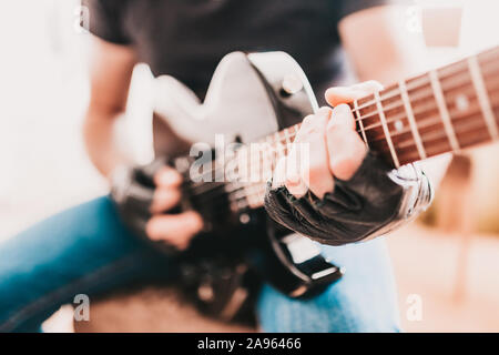 Bilanciere in black T-shirt e jeans giocando hard rock su un nero chitarra elettrica Foto Stock