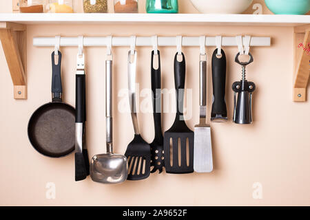 Diversi utensili da cucina appeso alla parete con decorazioni home Foto Stock