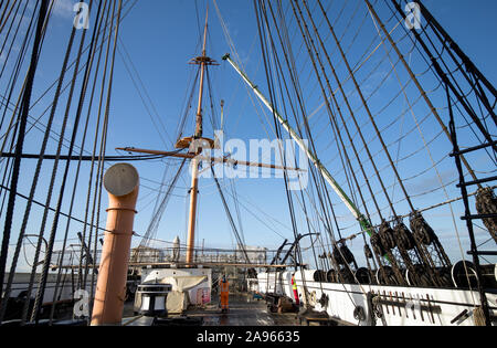 Il cantiere crossjack viene abbassata mediante gru dal mizzenmast sulla Corazzata Vittoriano HMS Warrior, ormeggiata a Portsmouth Historic Dockyard, le navi a montanti e parte del suo bompresso devono essere rimossi per restauro essenziale a Portsmouth. Foto Stock