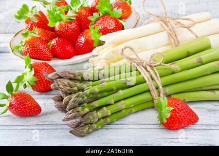 Gli asparagi e le fragole contro lo sfondo di legno Foto Stock