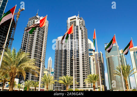 Dubai / Emirati Arabi Uniti - 11 Novembre 2019: vista dei grattacieli JLT con bandiere degli EMIRATI ARABI UNITI. Emirati Arabi Uniti bandiere sventolano sul cielo blu sullo sfondo. Giornata nazionale. Gruppo Foto Stock