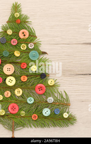 Albero di Natale fatto con rami di pino e pulsanti sul tavolo di legno Foto Stock