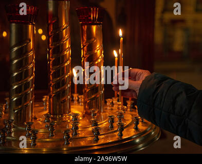 Donna illuminazione a mano candele in una chiesa Foto Stock