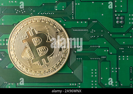 Close-up di golden Bitcoin verde sulla scheda di circuito stampato Foto Stock