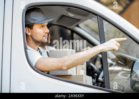 Consegna i dipendenti delle società di guida veicolo carico, la consegna delle merci ai clienti, bello courier puntando sul modo in avanti Foto Stock