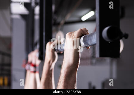 Primo piano dettaglio dei maschi di mani tenendo un pull-up bar in una palestra. Climbing, funzionali di formazione e di concorrenza. Foto Stock