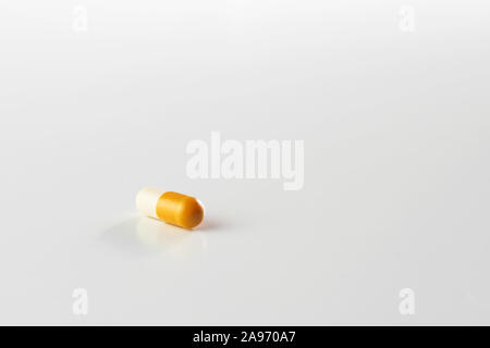 Primo piano del giallo e bianco capsula pillola isolati su sfondo bianco. La droga, farmacia, medicina e salute i concetti. Foto Stock