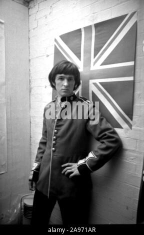 Un giovane uomo prova su una tunica di Grenadier militare in stile scarlatto Kitchener in una boutique in Kings Road, Chelsea durante l'oscillazione 60s di Londra Foto Stock