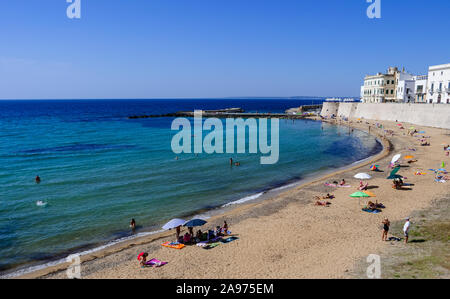 La gente a prendere il sole sulla spiaggia del porto del Mediterraneo presso il mare blu profondo Foto Stock