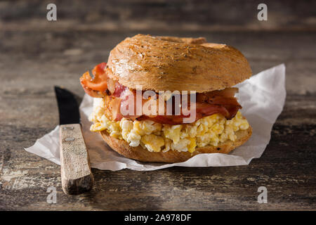 Bagel sandwich con lastra pancetta, uova e formaggio sul tavolo di legno Foto Stock