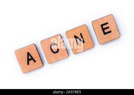 La parola acne, farro con lettera in legno piastrelle su uno sfondo bianco. Foto Stock