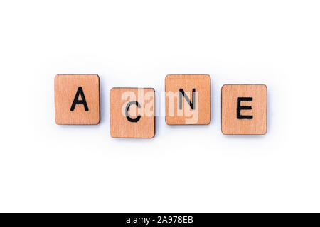 La parola acne, farro con lettera in legno piastrelle su uno sfondo bianco. Foto Stock