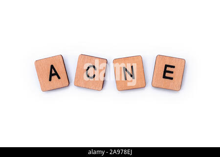 La parola acne, farro con lettera in legno piastrelle su uno sfondo bianco. Foto Stock