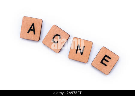 La parola acne, farro con lettera in legno piastrelle su uno sfondo bianco. Foto Stock