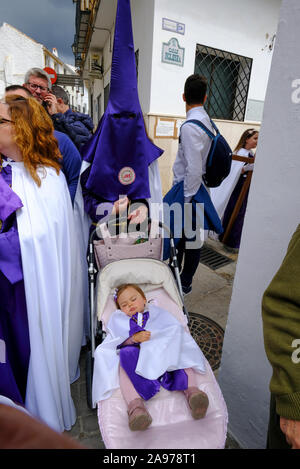 Processione della comunità locale che indossa i capiroti viola, portando Gesù e la Croce durante la settimana Santa. Carcabuey, Provincia di Cordova, Andalusia. Spagna Foto Stock