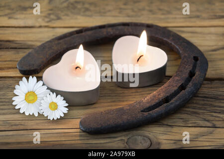 Il ferro di cavallo e candele contro lo sfondo di legno Foto Stock